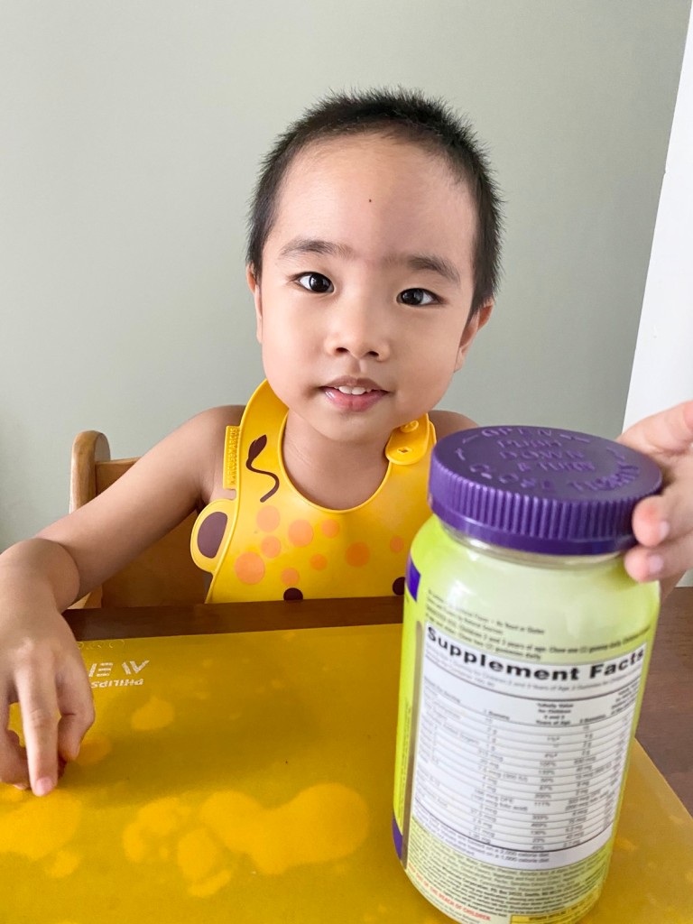 Toddler holding his jar of multivitamin gummies