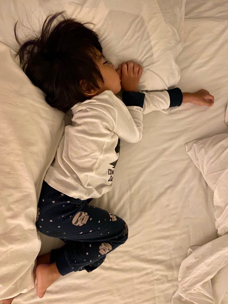 Little boy sleeping on a white bed
