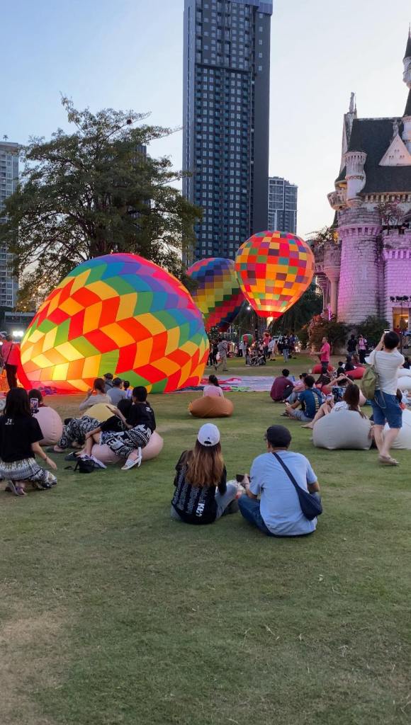 An open park with hot air balloons and people having picnics