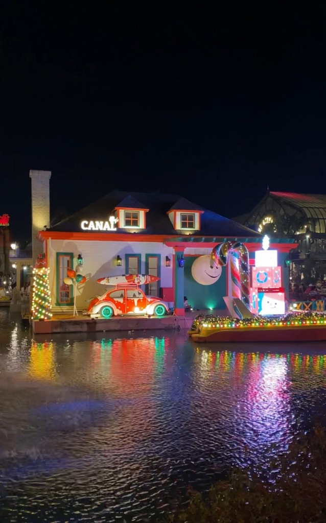 An amusement park with a quirky display house with cars and giant candy canes
