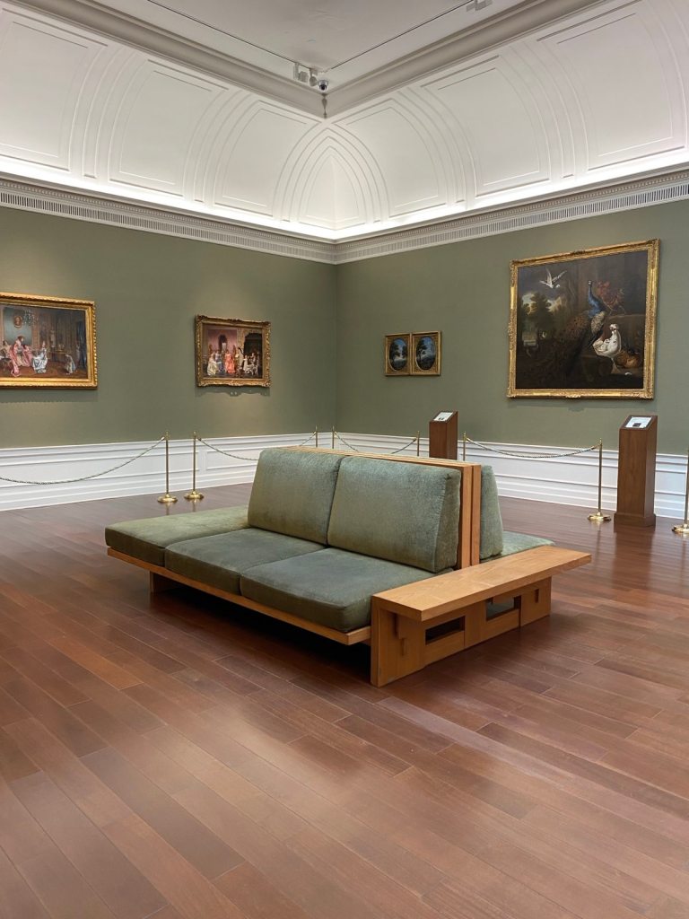 a cushioned seat in a museum surrounded by paintings