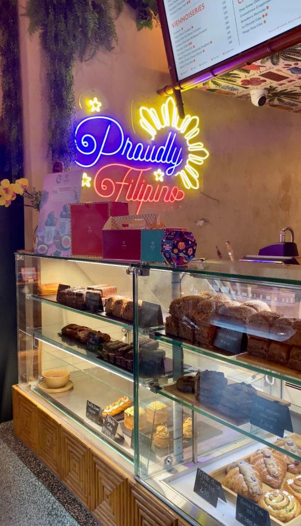 a shelf of baked goodies with a neon sign saying "proudly Filipino"